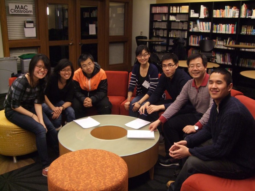 people sitting on a couch smile at the camera