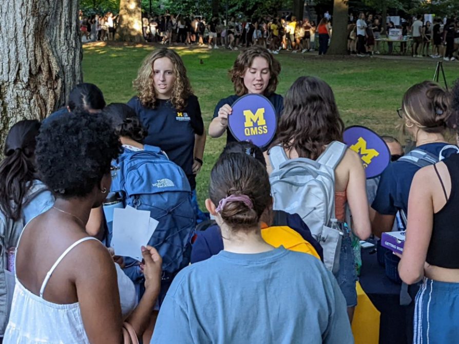 Students gather around a table outdoors to learn more about the QMSS minor and program.