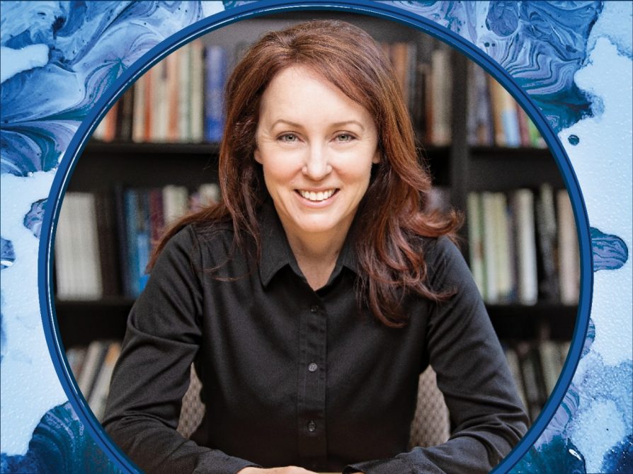 Anna Kirkland Smiles in a black shirt in front of a library of books framed by a swirl of blue