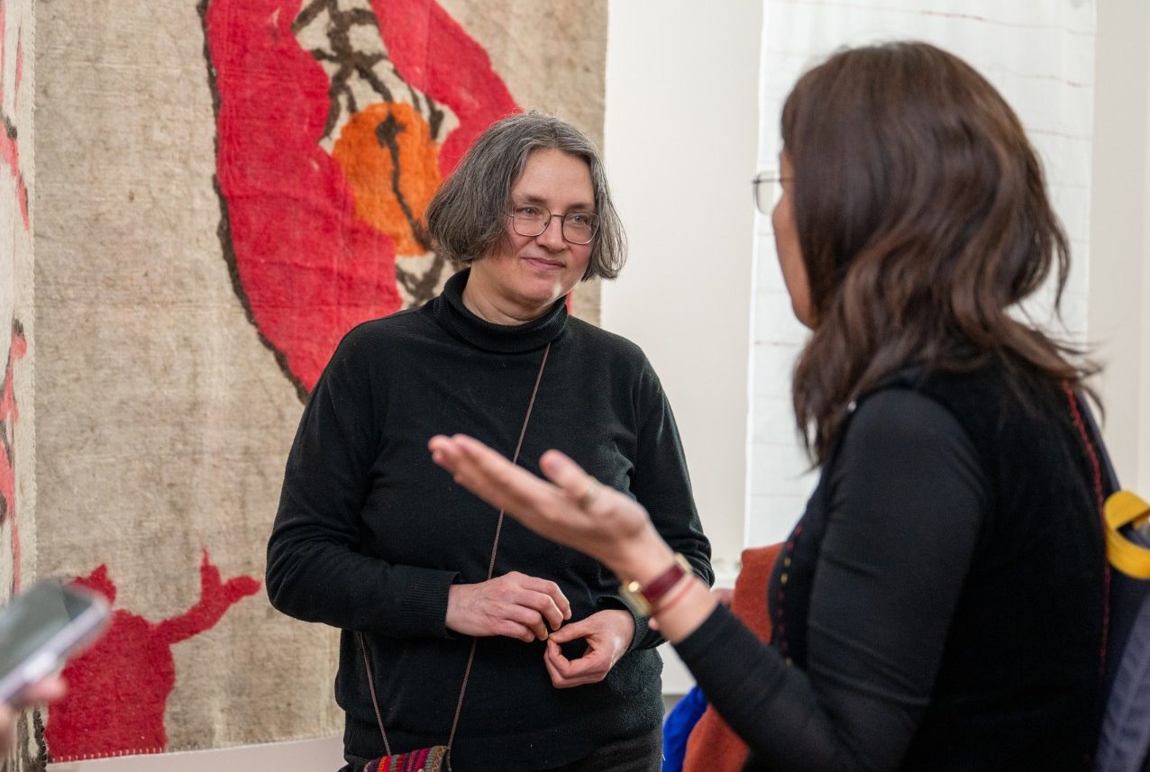 Gluklya engaging with community member at exhibit opening.