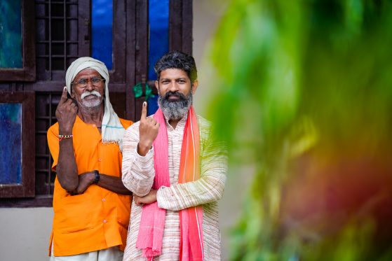 Two Indian men showing fingers after voting