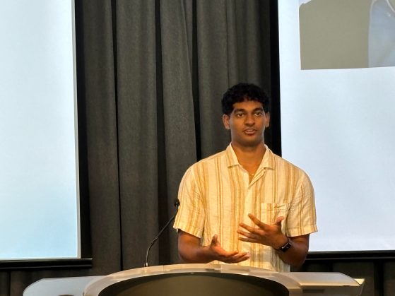 Student wearing a yellow shirt speaking at a podium