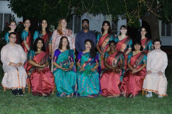 A group of people in colorful traditional Indian clothing pose together 