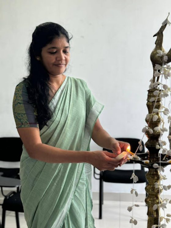 Pathima Pasmila Raviraj is holding a lit candle next to a string of florals