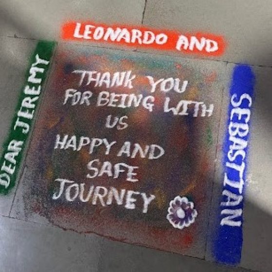 Painting on the sidewalk that says "Dear Jeremy, Leonardo, and Sebastian. Thank you for being with us. Happy and safe Journey. "