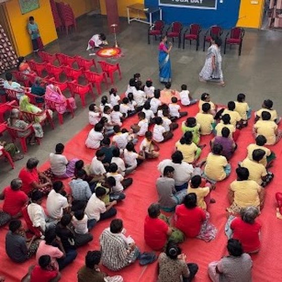 Aerial shot of a large classroom and students. There is a sign at the front that says "Yoga Day."