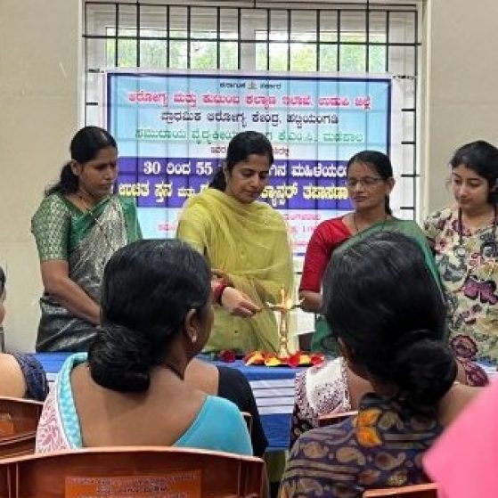 A group of people in traditional Indian dress are lighting a candle