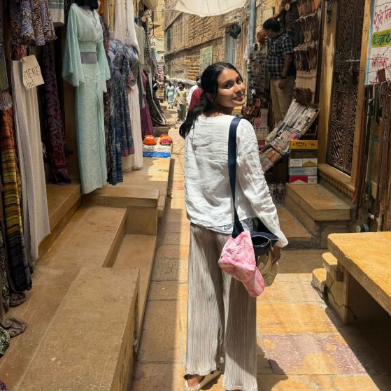Anika looking over her shoulder while walking through an outdoor market