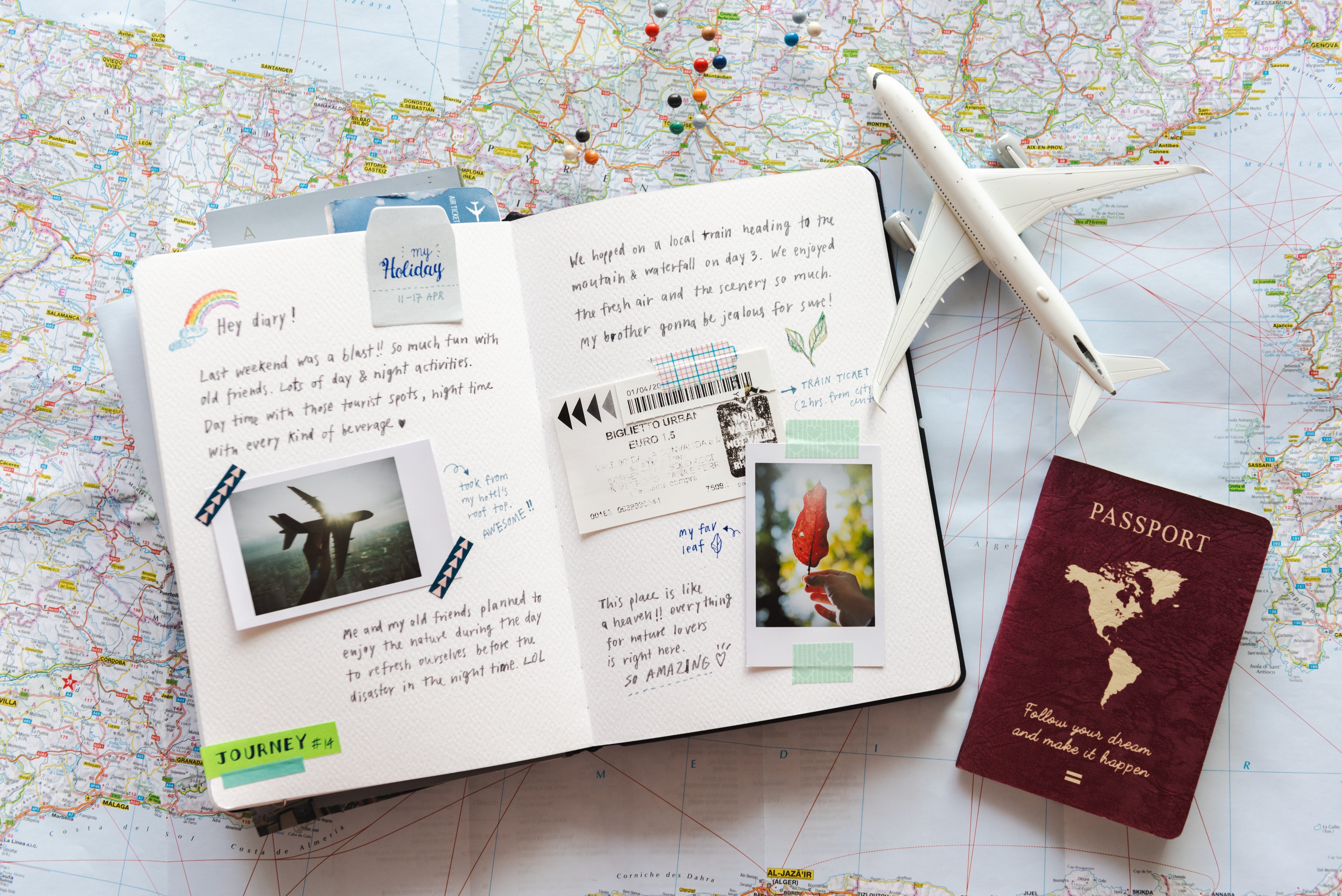 A journal with photos and a plane ticket is laid out on top of a world map with a toy airplane and passport.