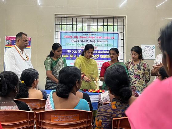 A group of people in traditional Indian dress are lighting a candle