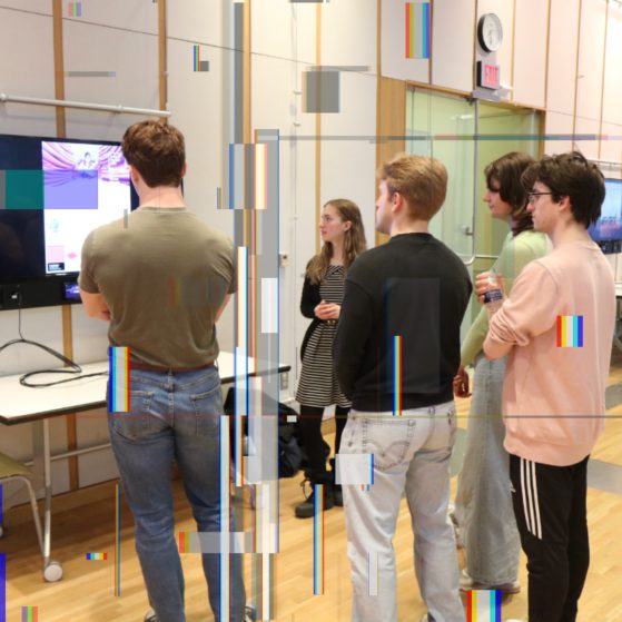 Digital Studies Institute students gathered around a monitor during a presentation. 