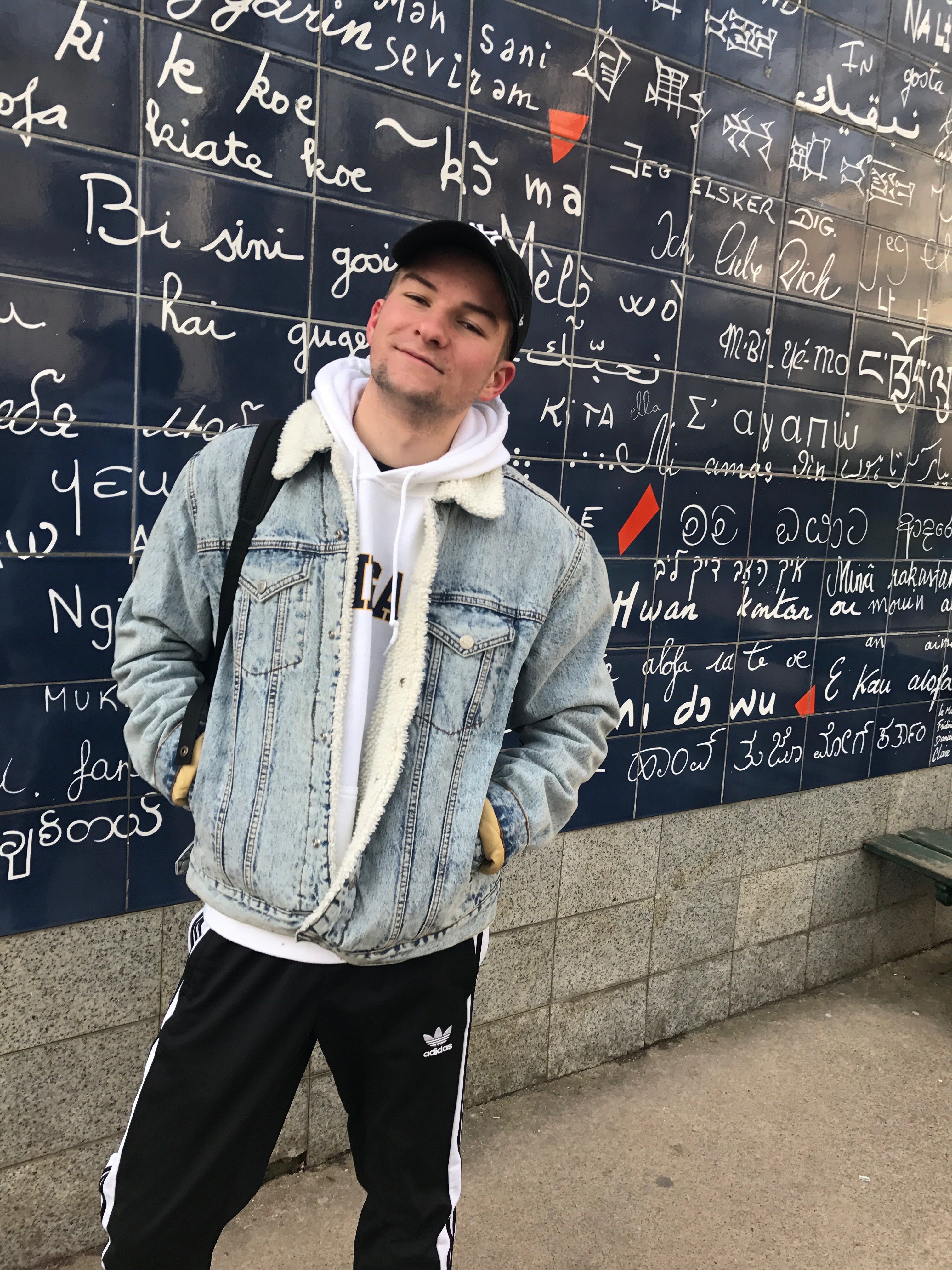 Ryan poses in front of a wall decorated with world languages. 