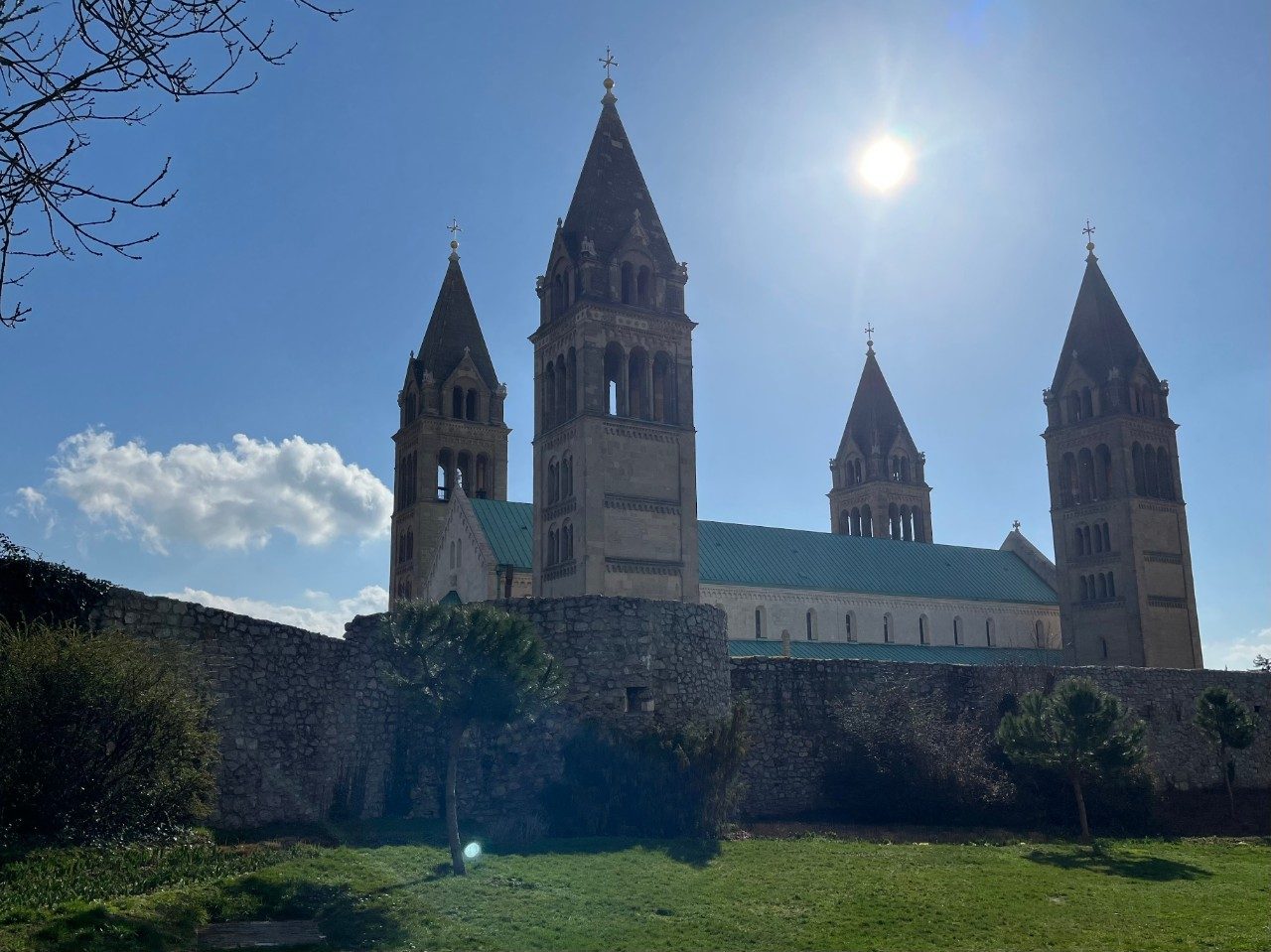 Sunny shot of the Pecs Cathedral exterior, with four impressive corner towers and a green roof.