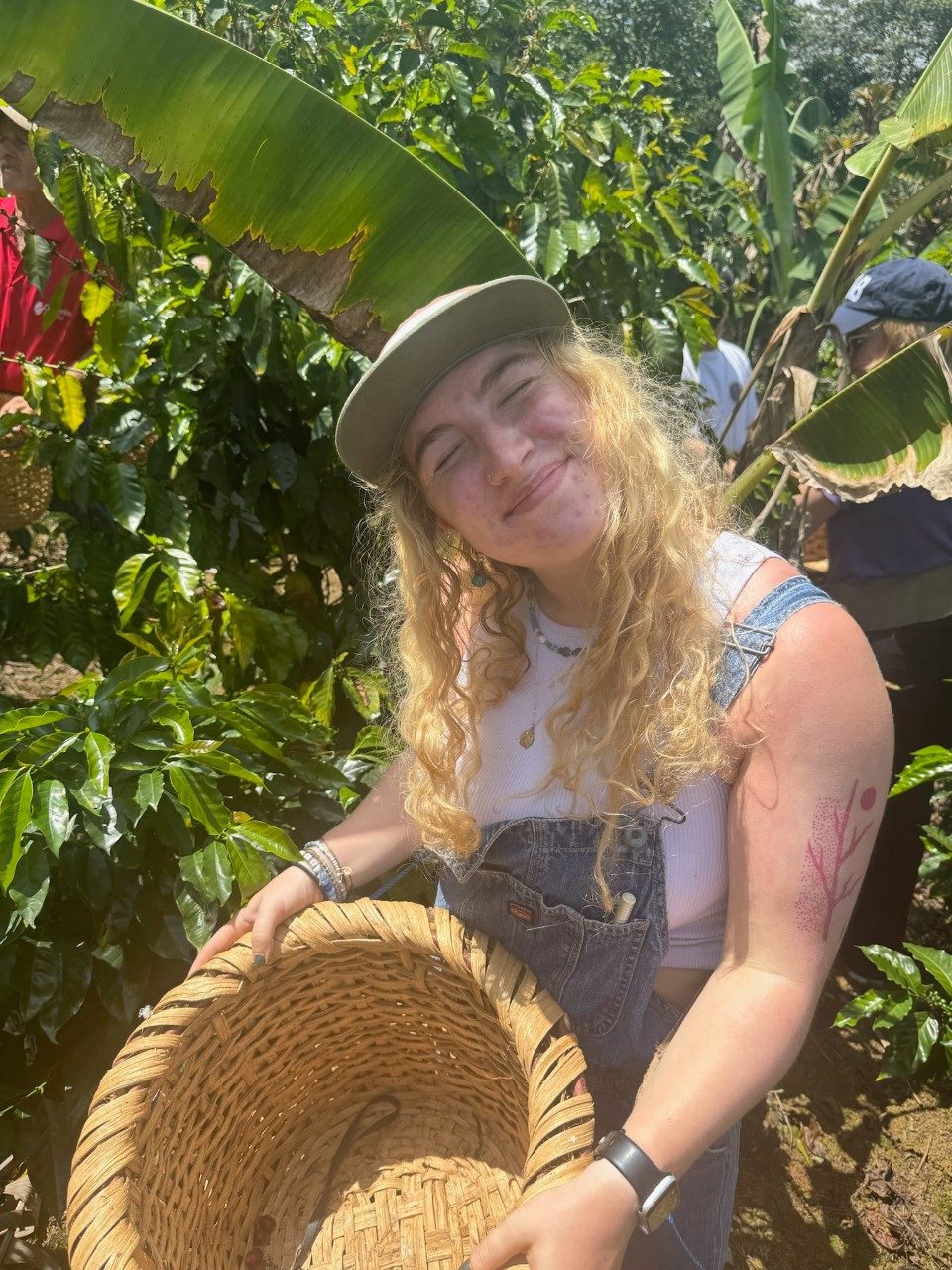 Cecelia at smiles while holding a basket outside at Café Calderon, a family owned coffee farm in Cartago, Costa Rica.