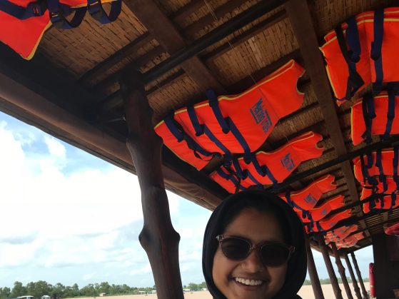 Tazia poses on a boat with a vibrant. red, roof.