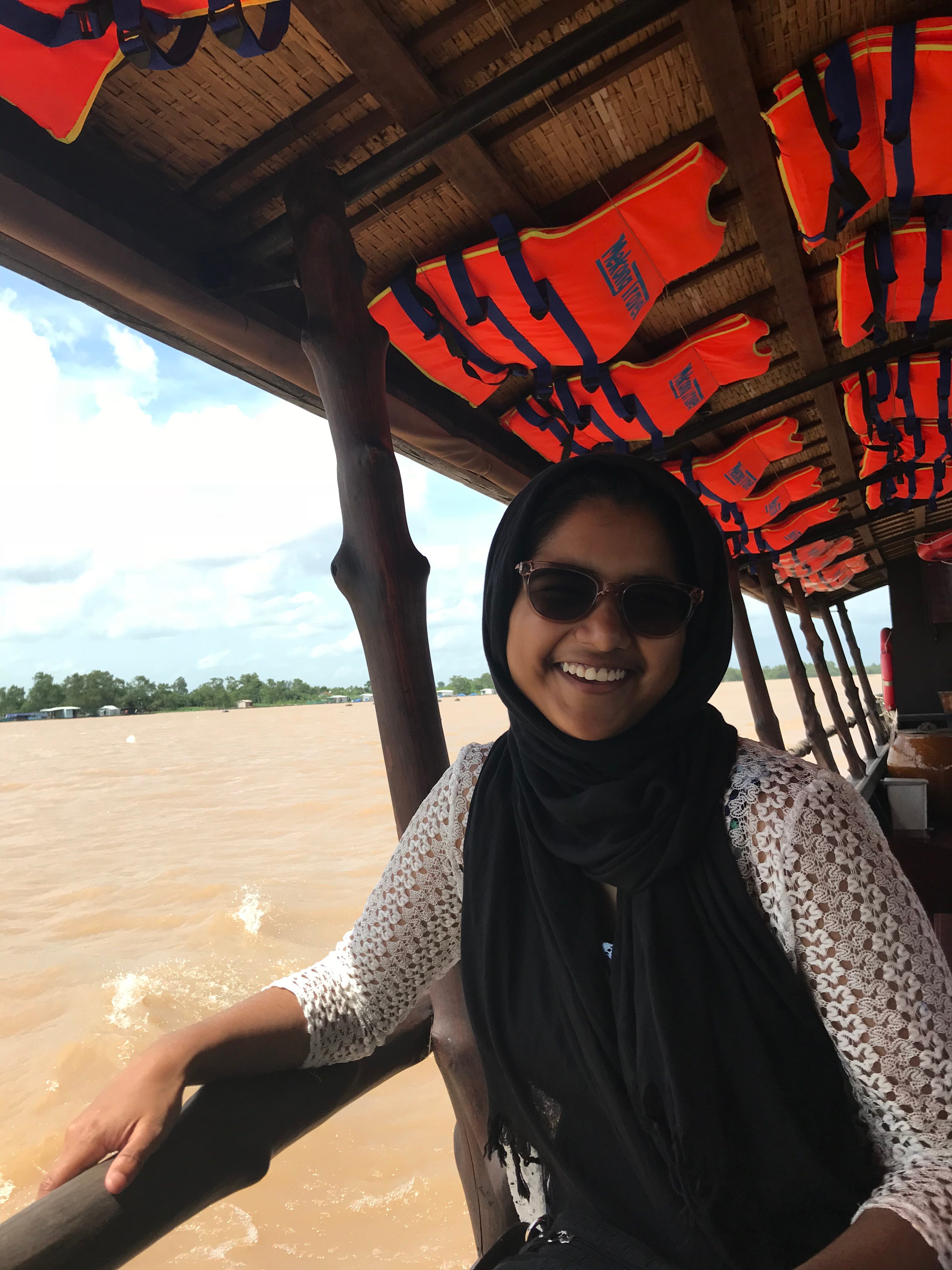 Tazia poses on a boat with a vibrant. red, roof.