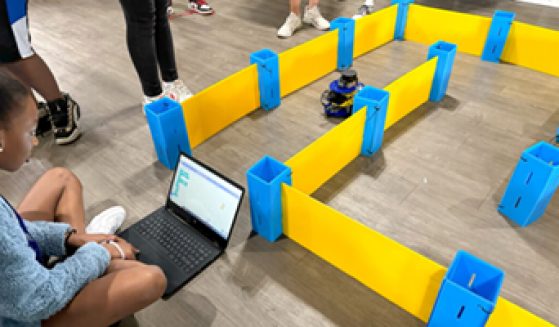 Image of young student manipulating robot running a course