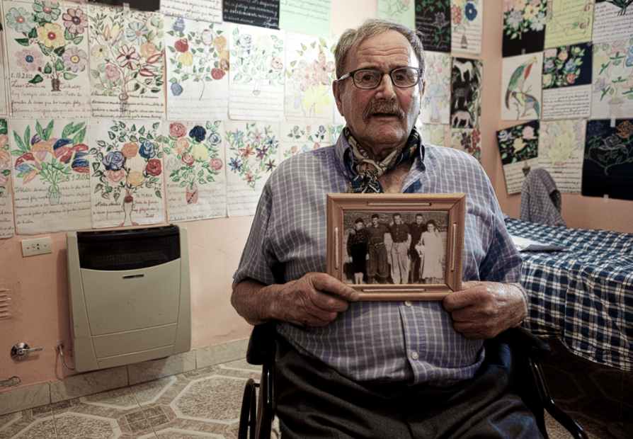 Agustin Dickason holding a black and white photograph of his ancestors. 