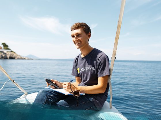 A photograph of Sebastian Kasparian sitting at the stern of a boat out on the open water.