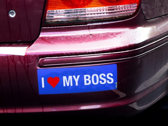 A photograph of a car bumper with a bumper sticker that says I heart my boss.