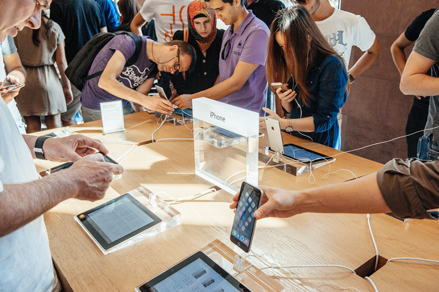 Shoppers at an Apple store investigating iPads and iPhones