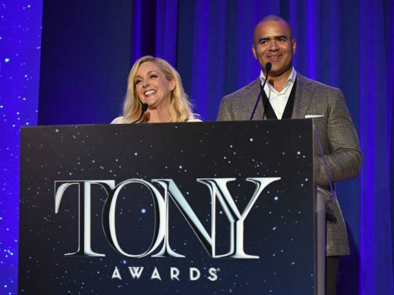 Actors Jane Krakowski and Christopher Jackson speak behind a podium that says Tony Awards. There is a bright blue curtain behind them. The photograph was taken during the 2017 Tony Awards Nominations Announcement.