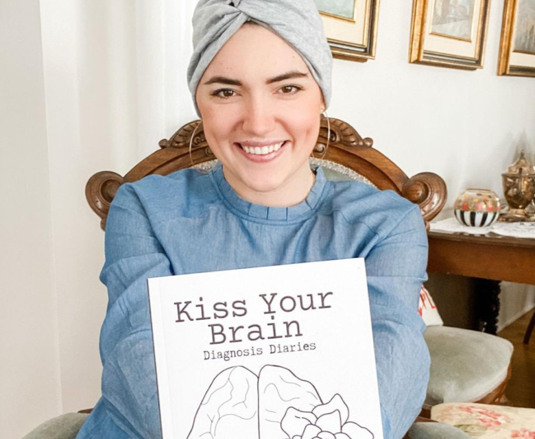 A photograph of Christina Costa holding her book, “Kiss Your Brain.”