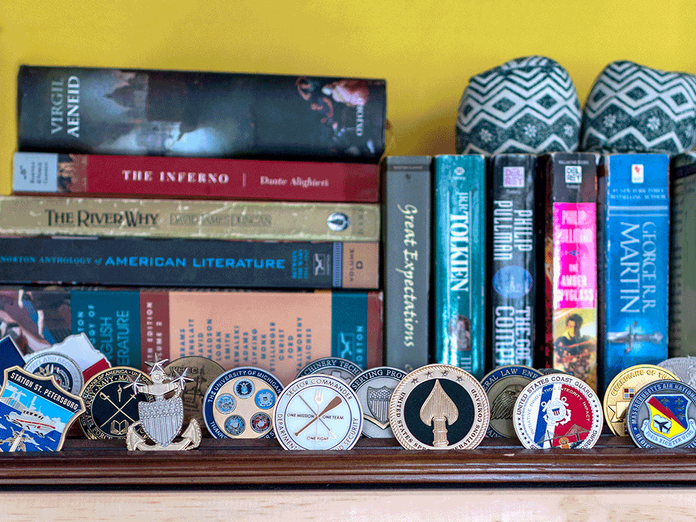 Image of a bookshelf in Pinkham's home that displays the challenge coins she received while in the Coast Guard. These are multi-colored, painted medallions that are given by unit commanders to recognize special achievements.