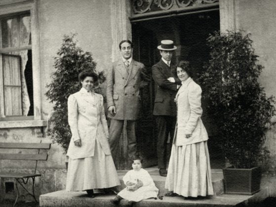 A photograph of musician and educator Bertha Hansbury posing with three other adults and a child, in front of a building and some greenery in Berlin, Germany. 
