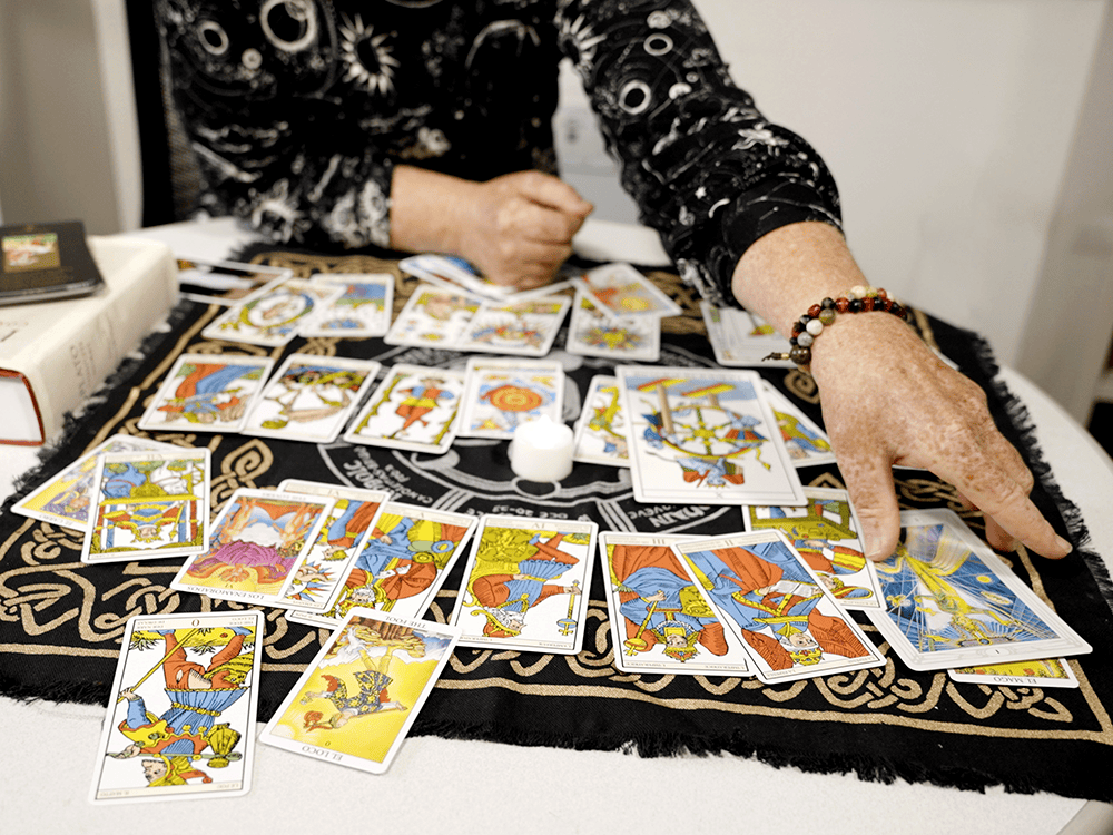 Two hands on a table spread with tarot cards.