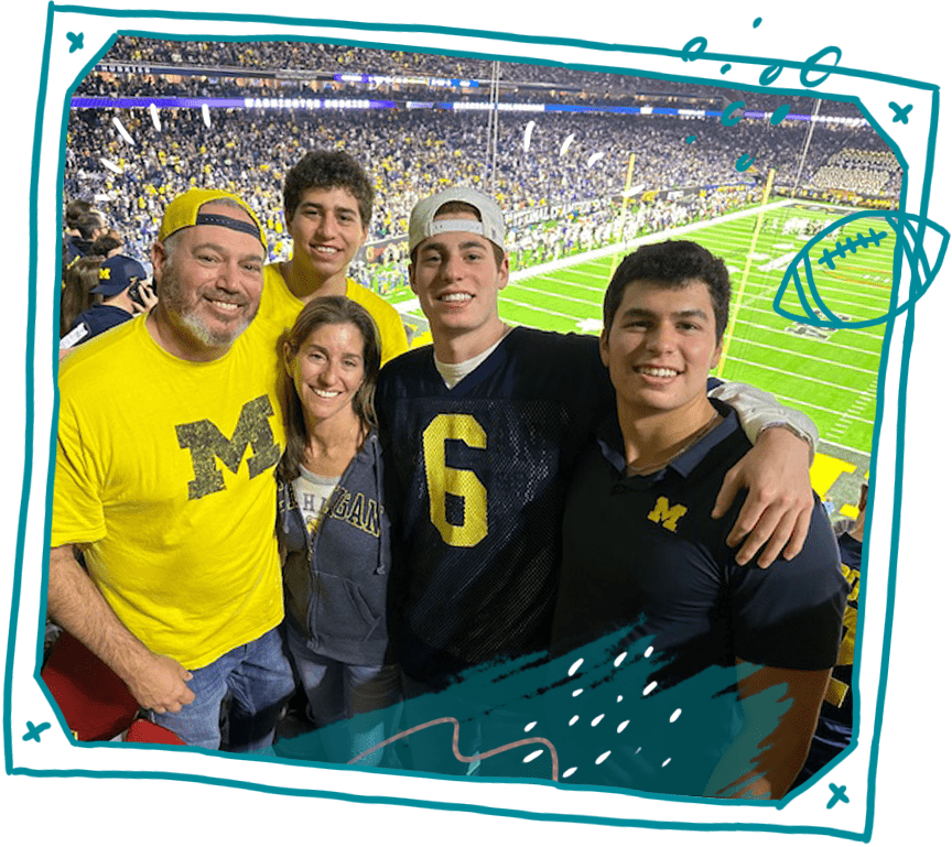 Five members of a family wearing University of Michigan gear pose for a photo in a football stadium. 