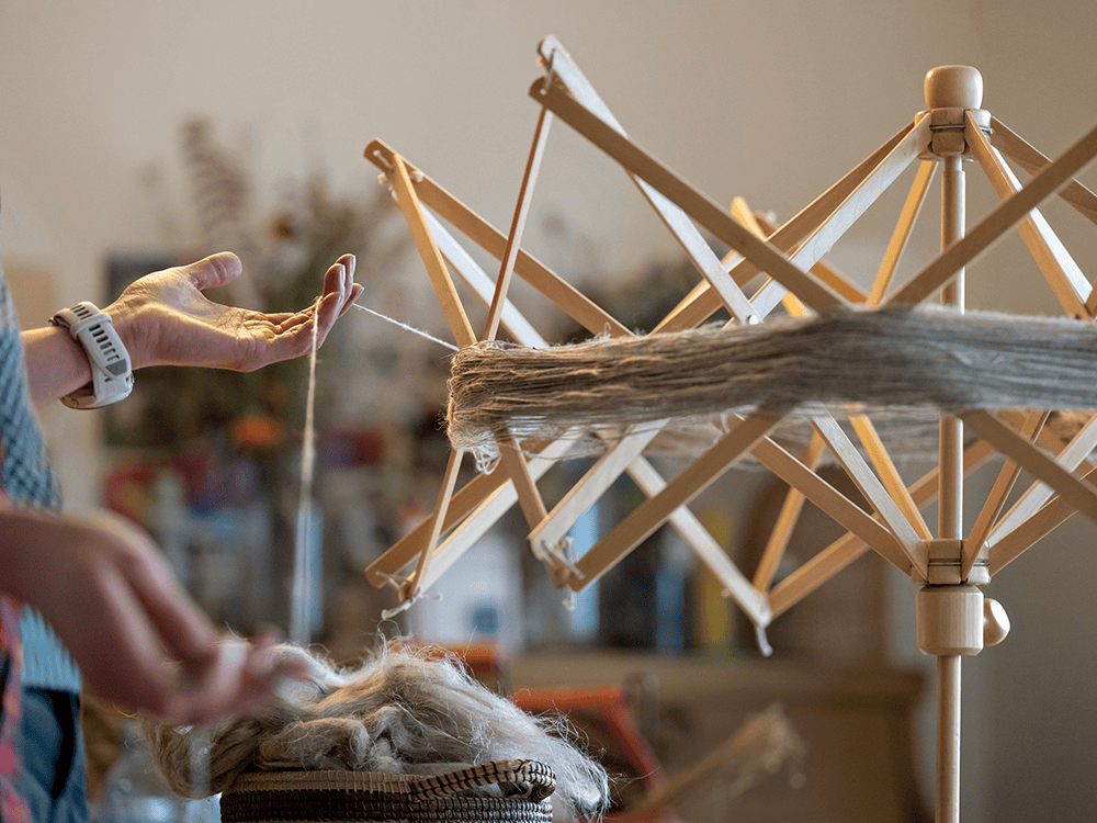 A photograph of a person winding linen yarn on her umbrella swift. 