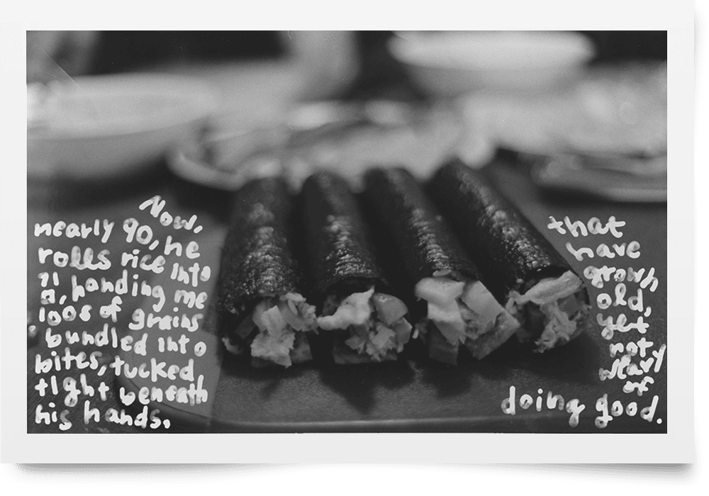 A black and white photograph of four handmade rolls of gim—dried seaweed—and rice on a plate. White ink handwriting overlays the photograph.