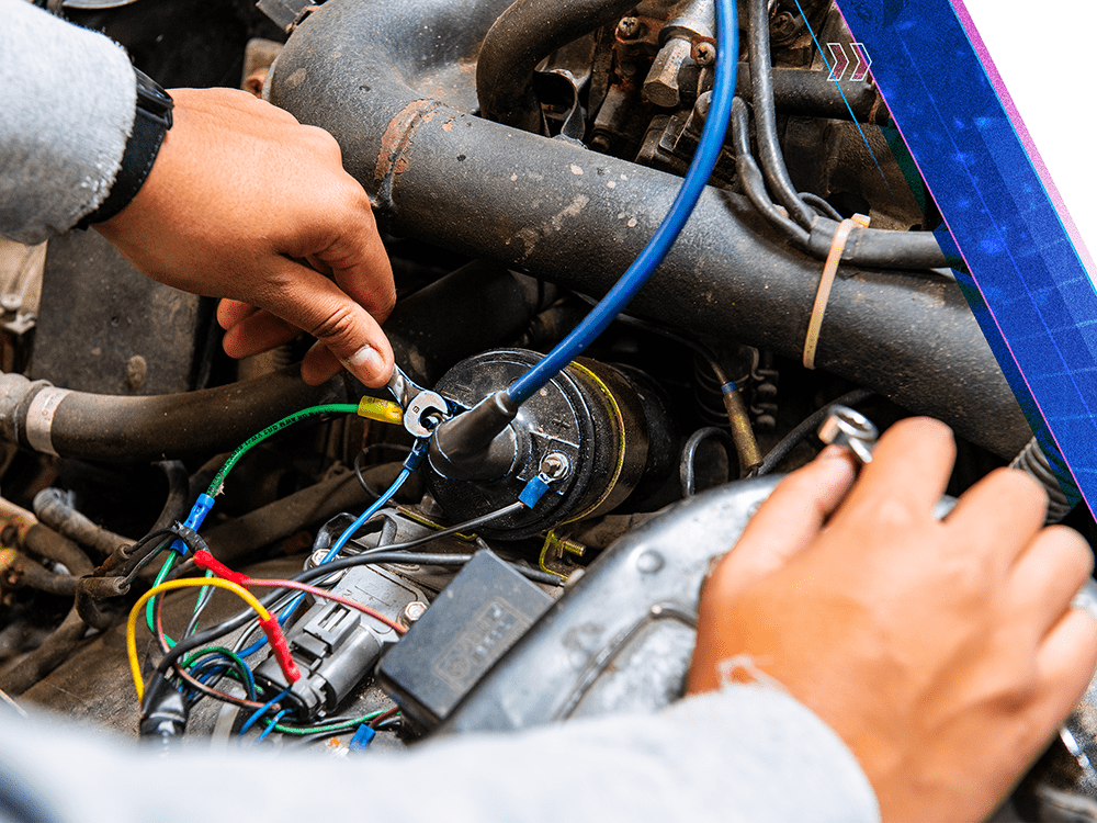 A close-up photograph of a person’s hands working under the hood of a car.