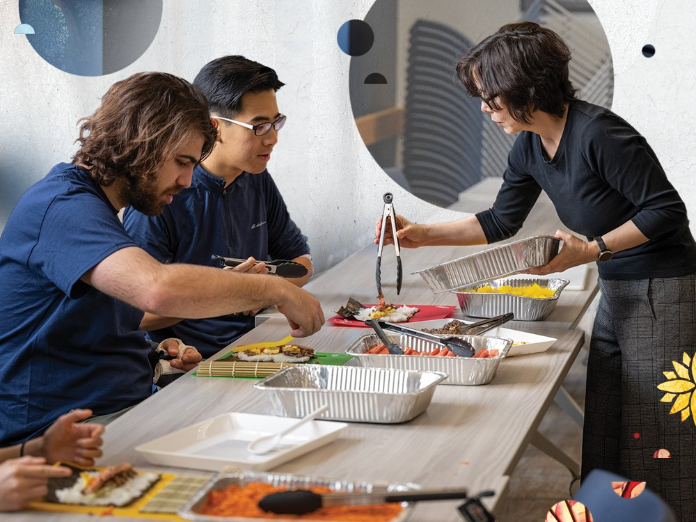 A photograph of two students assembling kimbap with Prof. Brown. 