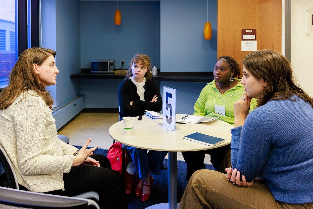 People sit around talking at a small table with a large number 5 sign in the center