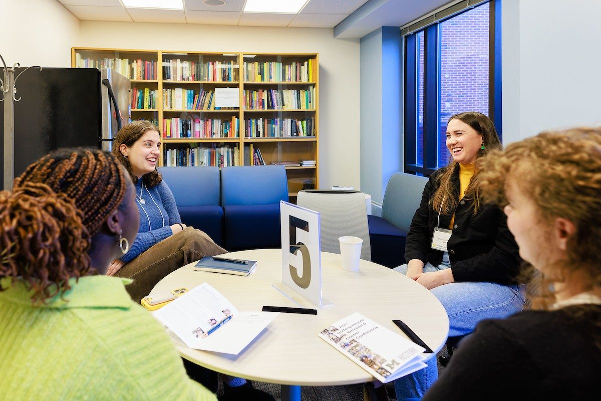 People laughing sitting around a table with a large number 5 in the center.