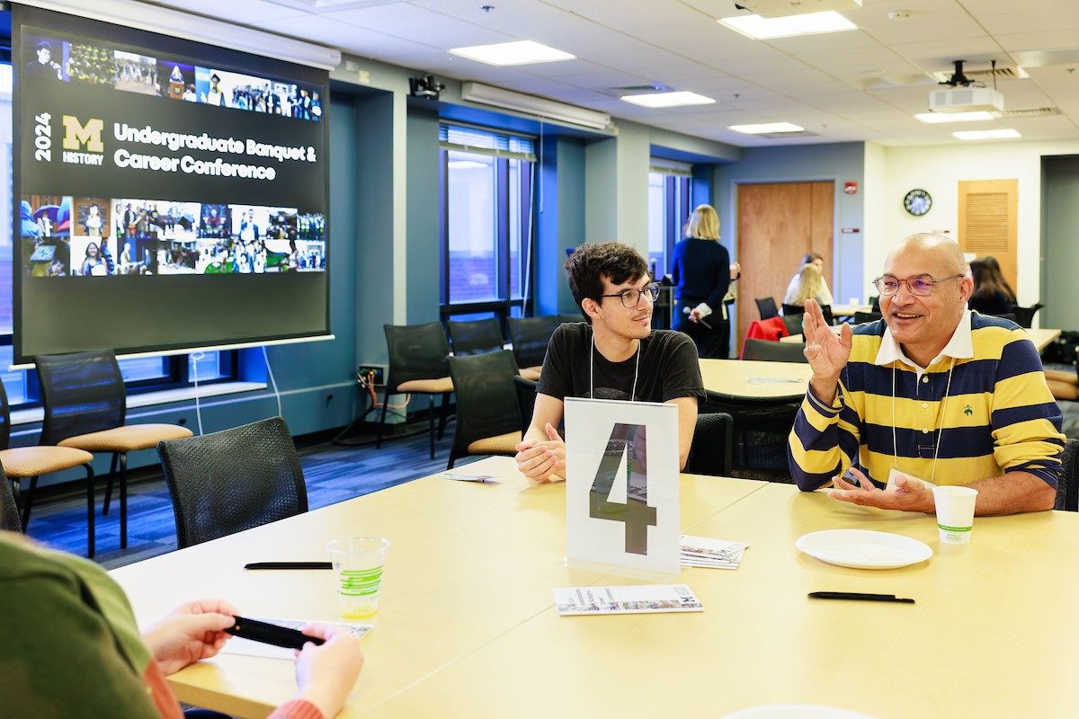Two people sit at a table with a large number 4 in the center.