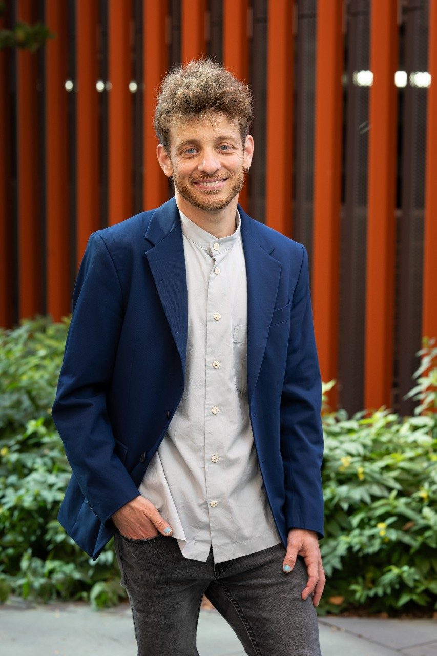 man with short brown hair and blue eyes wearing a navy blazer poses smiling for a professional headshot