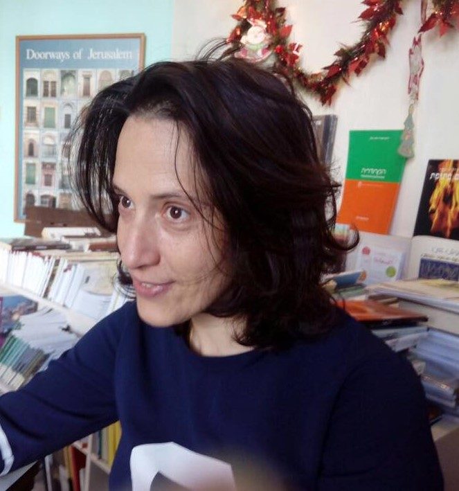 Woman with shoulder-length brown hair sits in her office looking off to the left