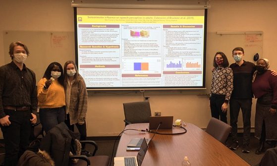 Students stand beside Sensorimotor research poster