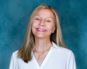 a white woman with shoulder-length straight blonde hair smiles excitedly