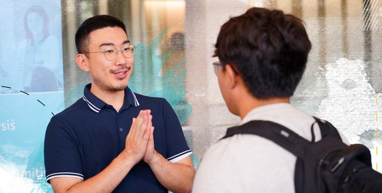 Employer with glasses talking with student, while holding their hands together