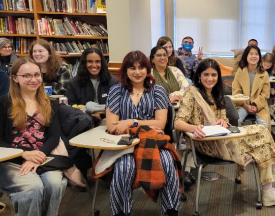 students sit in a classroom smiling at the camera