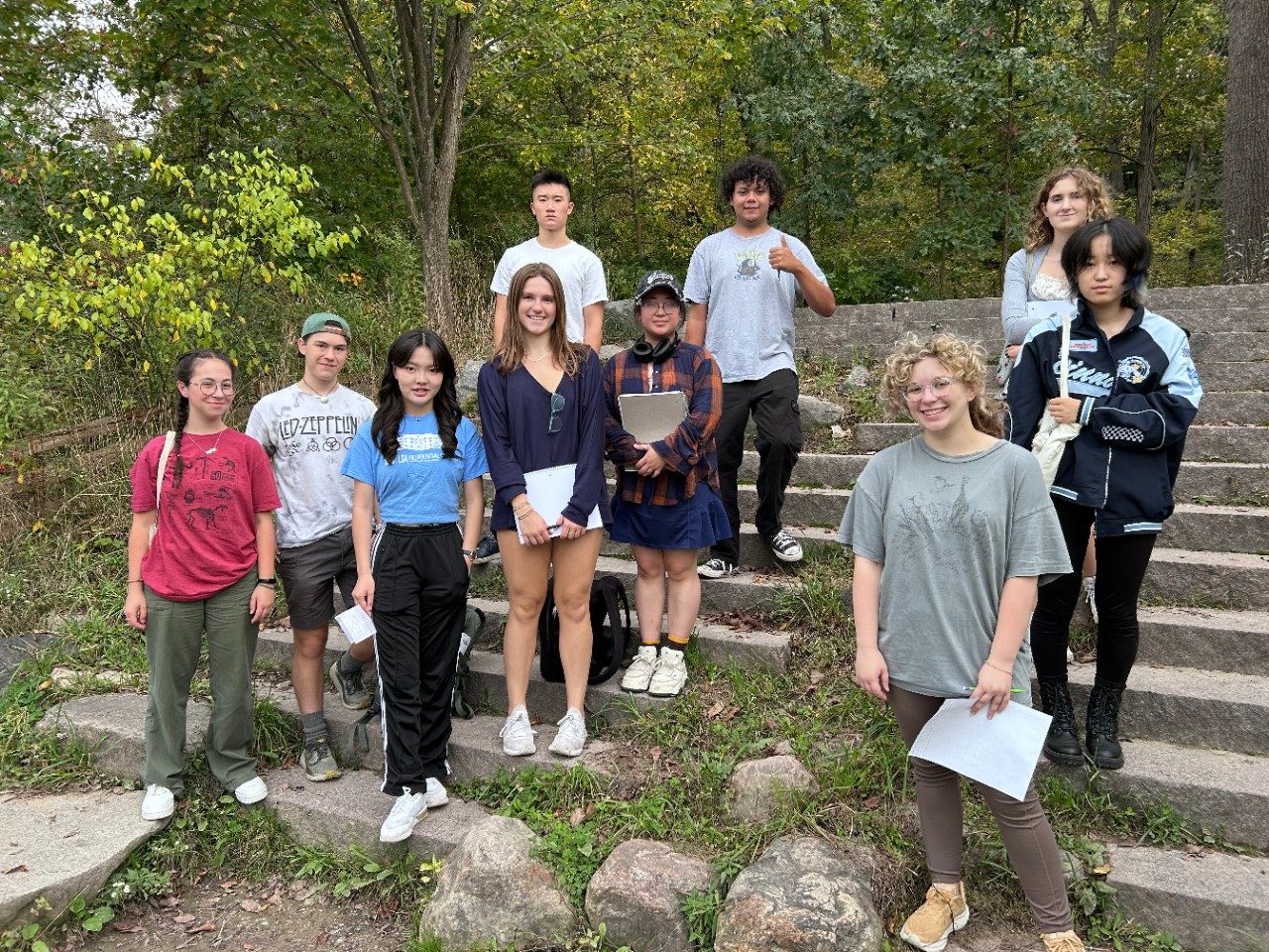 students stand in a group on a stone staircase in the woods