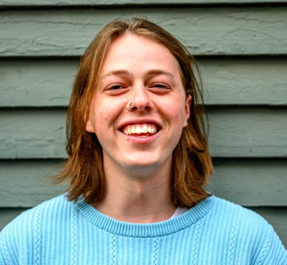student in blue sweater smiling at camera