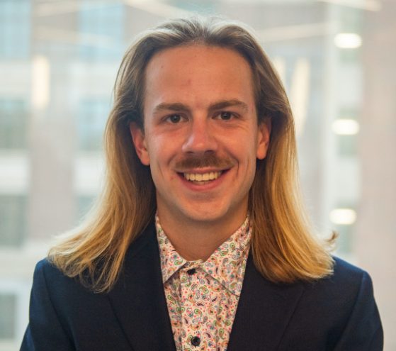 male in blue suit jacket smiling at camera
