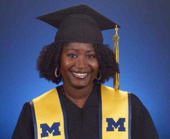 female in grad gown and cap smiling at camera