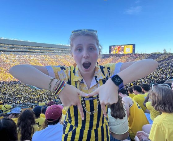 female in blue and maize striped overalls smiling at camera