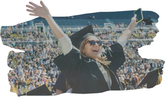 graduate with arms in air at commencement
